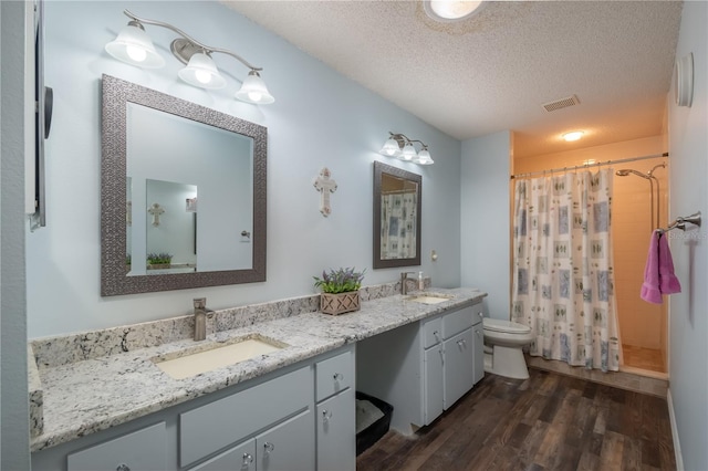 bathroom featuring vanity, toilet, hardwood / wood-style floors, and a textured ceiling