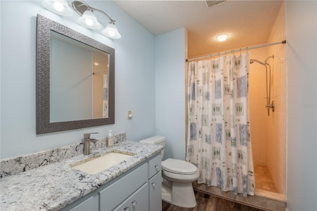 bathroom with toilet, a textured ceiling, wood-type flooring, curtained shower, and vanity