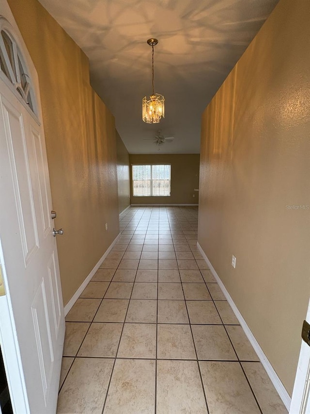 hallway featuring an inviting chandelier and light tile patterned floors