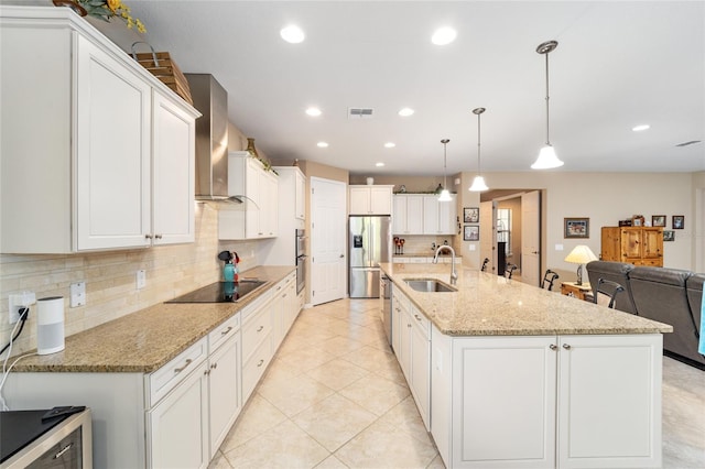 kitchen with wall chimney exhaust hood, decorative light fixtures, a spacious island, appliances with stainless steel finishes, and sink