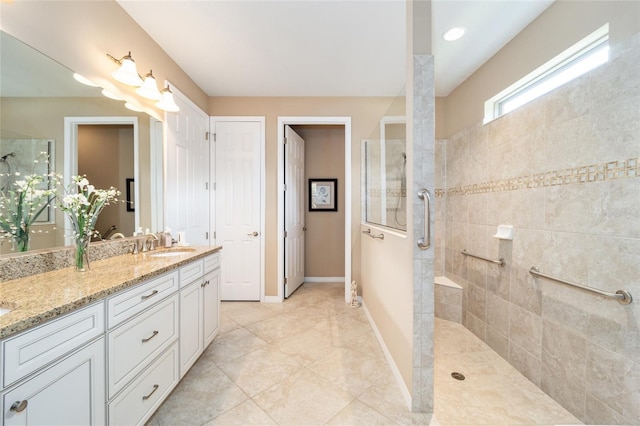 bathroom featuring tile patterned flooring, tiled shower, and vanity