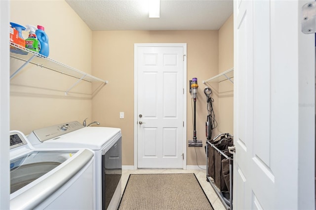 laundry room featuring separate washer and dryer, a textured ceiling, and light tile patterned floors