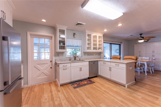 kitchen with sink, white cabinetry, light wood-type flooring, and appliances with stainless steel finishes