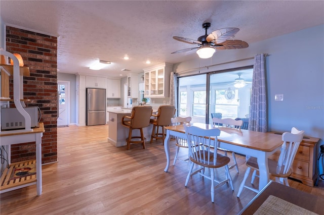 dining room featuring a textured ceiling, ceiling fan, and light hardwood / wood-style flooring