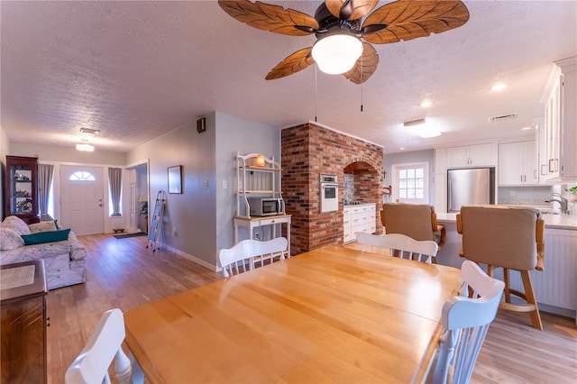 dining area featuring sink, a textured ceiling, and light hardwood / wood-style floors