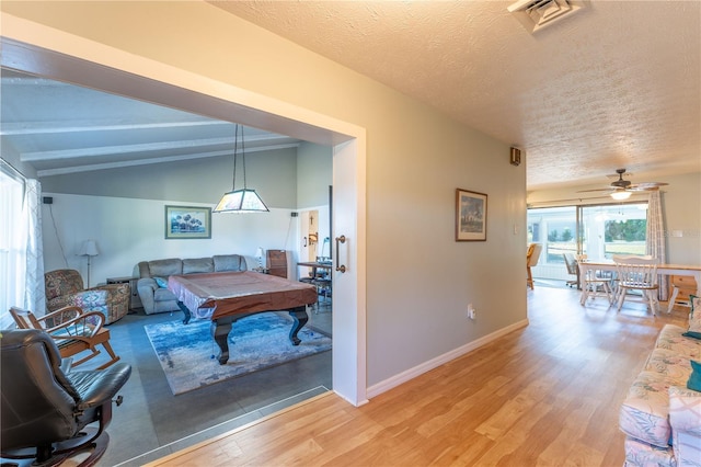 game room featuring a textured ceiling, ceiling fan, lofted ceiling with beams, and wood-type flooring