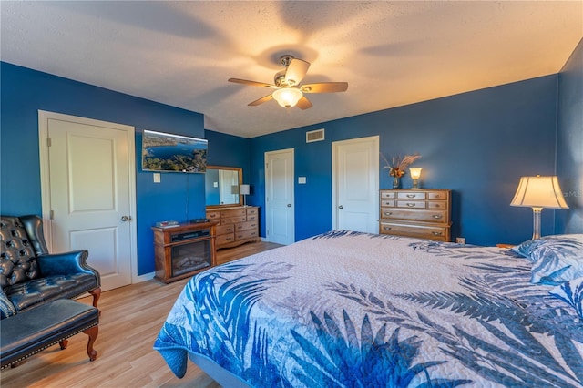 bedroom with a textured ceiling, ceiling fan, and light wood-type flooring