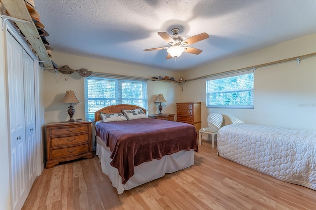 bedroom featuring multiple windows, a closet, ceiling fan, and light hardwood / wood-style flooring