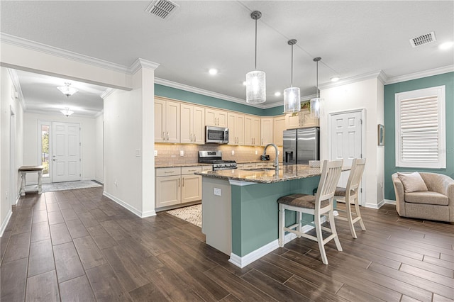 kitchen with backsplash, a kitchen island with sink, a kitchen breakfast bar, stainless steel appliances, and light stone counters