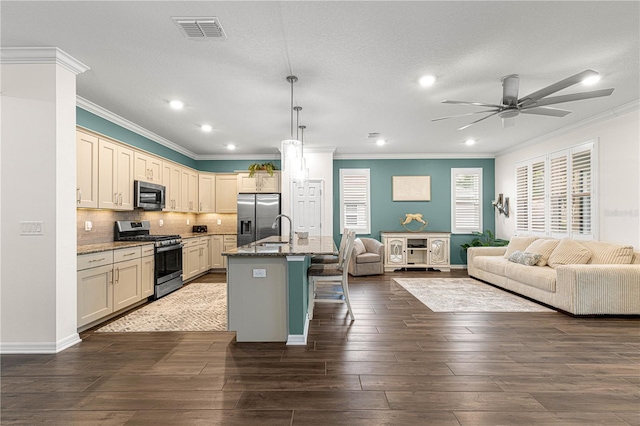 kitchen with a kitchen bar, a center island with sink, stainless steel appliances, hanging light fixtures, and light stone counters