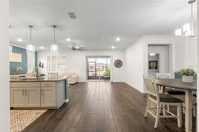 kitchen featuring dark stone countertops, ceiling fan with notable chandelier, pendant lighting, and sink