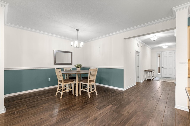 dining room featuring a textured ceiling, dark wood-type flooring, ornamental molding, and a notable chandelier