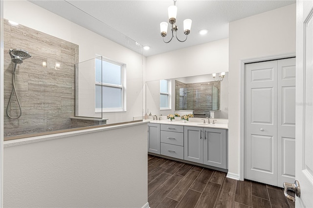 bathroom featuring vanity, a chandelier, and a tile shower