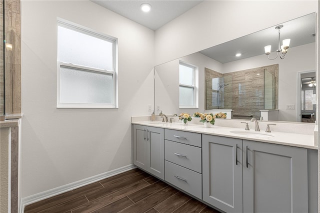 bathroom featuring tiled shower, vanity, and a notable chandelier