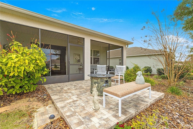 view of patio with an outdoor fire pit and a sunroom