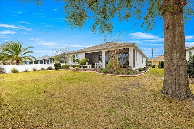 rear view of property with a sunroom and a lawn