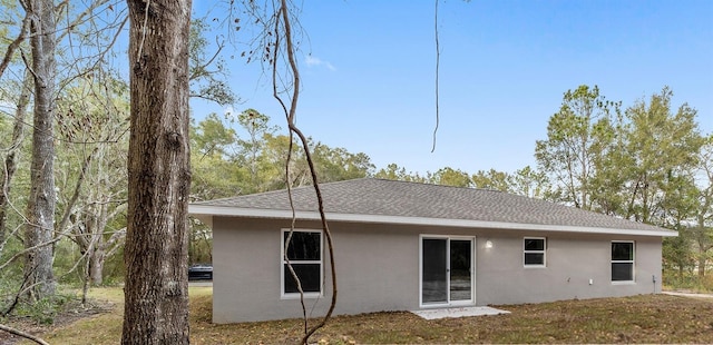 rear view of house featuring stucco siding and a shingled roof