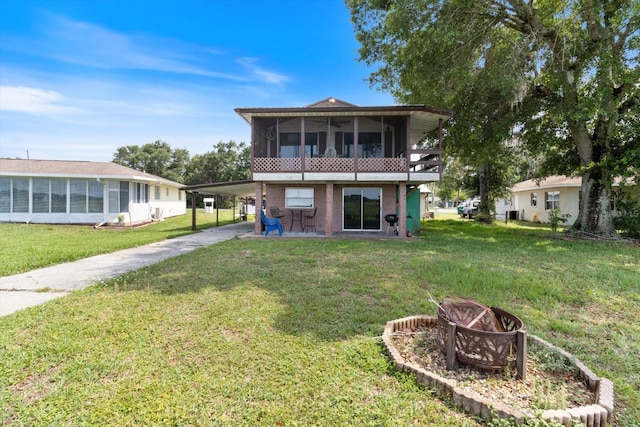 rear view of house with a carport, a yard, and a sunroom