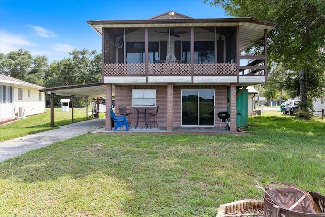 rear view of property with ceiling fan, a yard, a carport, and a sunroom