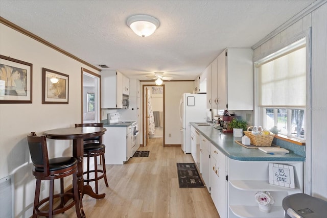 kitchen with white appliances, a textured ceiling, crown molding, and white cabinetry