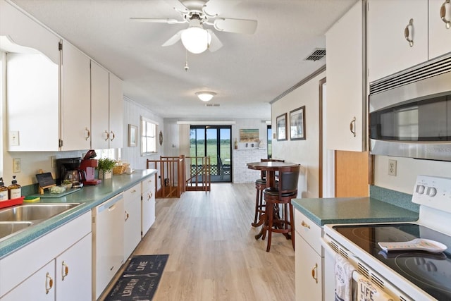 kitchen featuring white appliances, a textured ceiling, light wood-type flooring, and white cabinetry