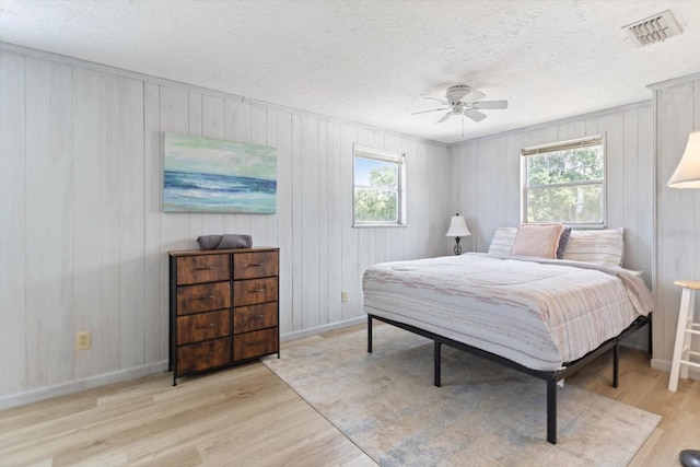 bedroom featuring light wood-type flooring, ceiling fan, and a textured ceiling