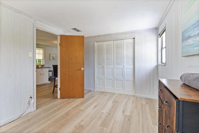 bedroom with a textured ceiling, a closet, light hardwood / wood-style flooring, and multiple windows