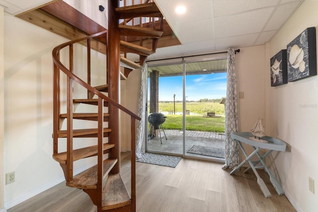 doorway to outside featuring a drop ceiling and light hardwood / wood-style flooring