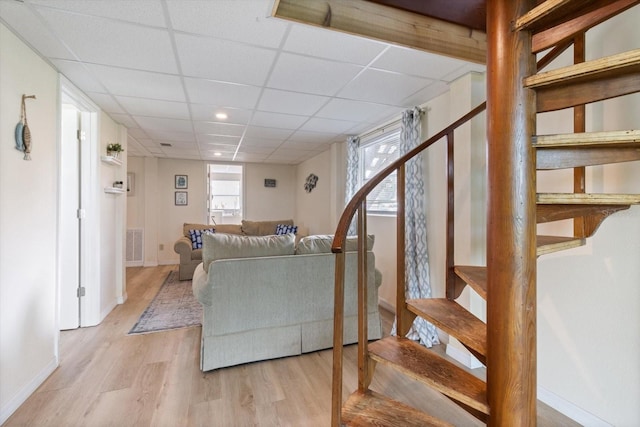 living room featuring light wood-type flooring and a drop ceiling