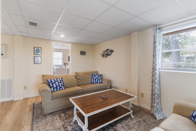 living room with washer and clothes dryer, a drop ceiling, light hardwood / wood-style floors, and plenty of natural light