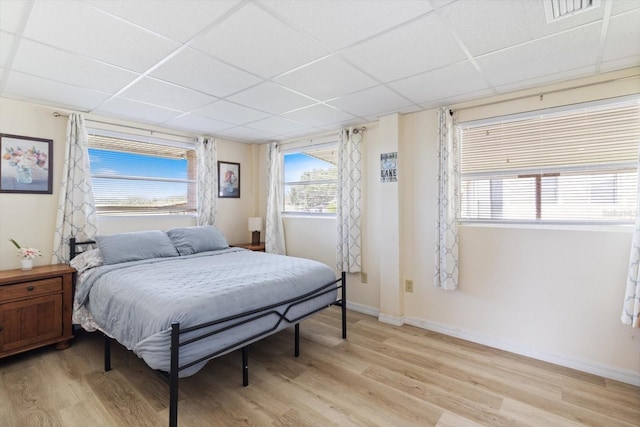 bedroom with light hardwood / wood-style flooring and a drop ceiling