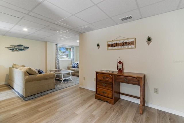 living area featuring light wood-type flooring and a drop ceiling