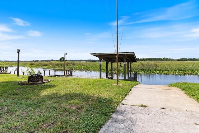 dock area featuring an outdoor fire pit, a lawn, and a water view