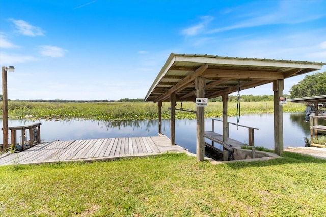 view of dock with a yard and a water view