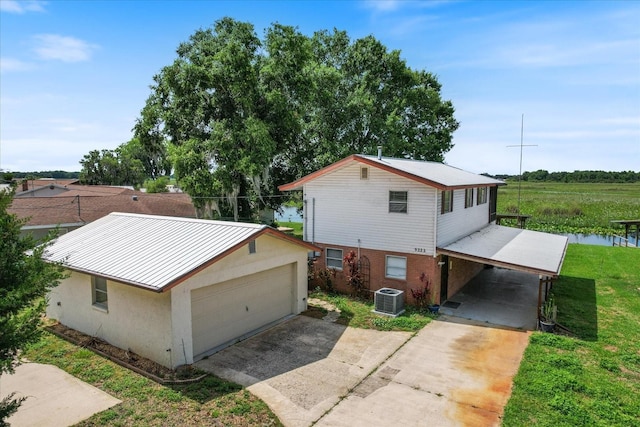 view of property exterior with a lawn, a garage, a water view, a carport, and central AC unit