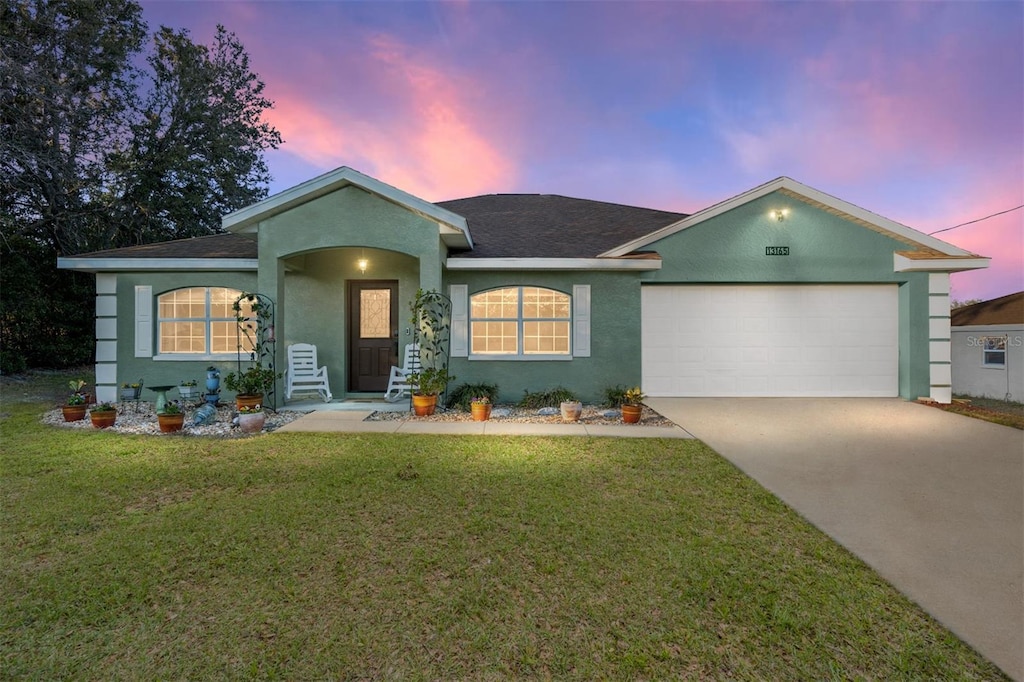 single story home featuring a lawn and a garage