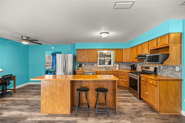 kitchen featuring stainless steel appliances, a breakfast bar, wooden counters, and a kitchen island