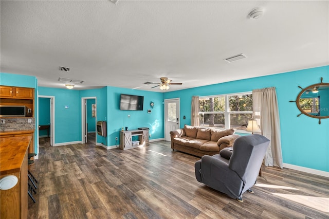 living room with dark wood-type flooring, ceiling fan, and a textured ceiling