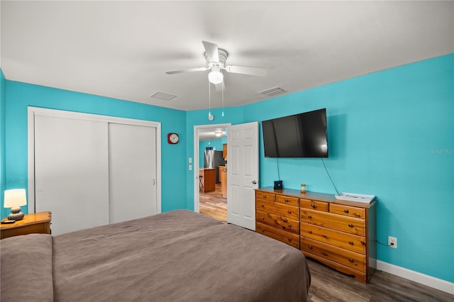 bedroom featuring stainless steel refrigerator, ceiling fan, dark hardwood / wood-style floors, and a closet