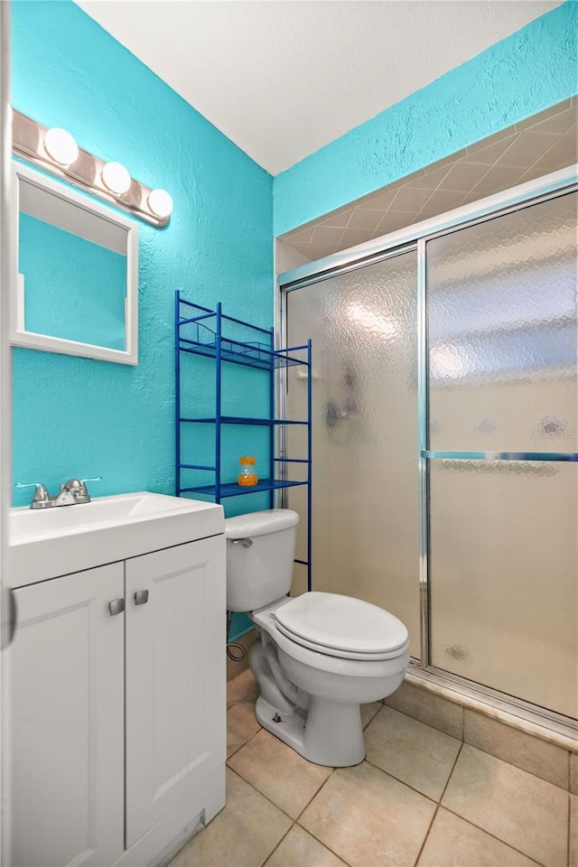 bathroom featuring tile patterned floors, toilet, a shower with shower door, and vanity