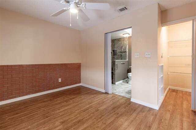 10918 SE 50th Ave, Belleview, FL 34420 - spare room featuring a textured ceiling, ceiling fan, brick wall, and light hardwood / wood-style floors