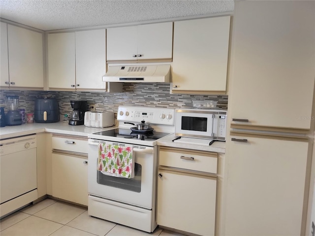 kitchen featuring light tile patterned floors, custom exhaust hood, decorative backsplash, white appliances, and a textured ceiling