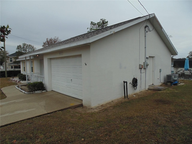 view of side of property featuring cooling unit, a yard, and a garage