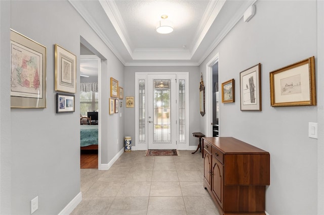 foyer entrance with light tile patterned floors, a textured ceiling, a tray ceiling, and ornamental molding