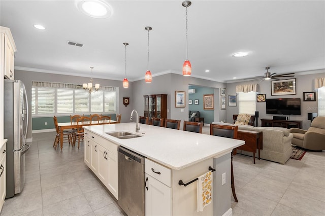 kitchen with decorative light fixtures, white cabinetry, an island with sink, stainless steel appliances, and ceiling fan with notable chandelier