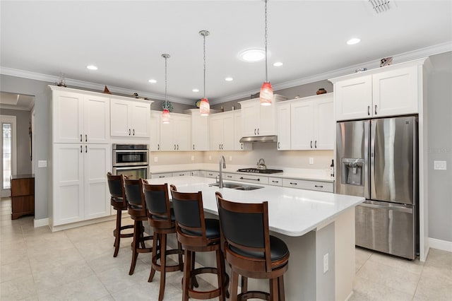 kitchen with a center island with sink, crown molding, hanging light fixtures, appliances with stainless steel finishes, and white cabinets