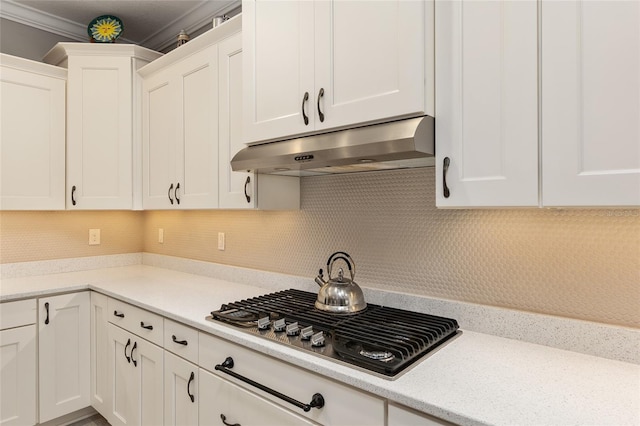 kitchen featuring white cabinets, stainless steel gas stovetop, ornamental molding, and tasteful backsplash