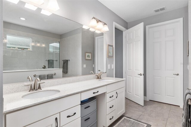 bathroom featuring tile patterned floors, tiled shower, and vanity