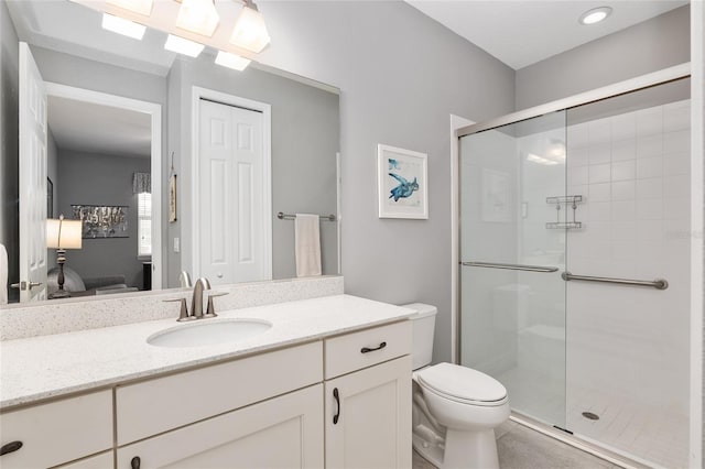 bathroom with an enclosed shower, vanity, and toilet