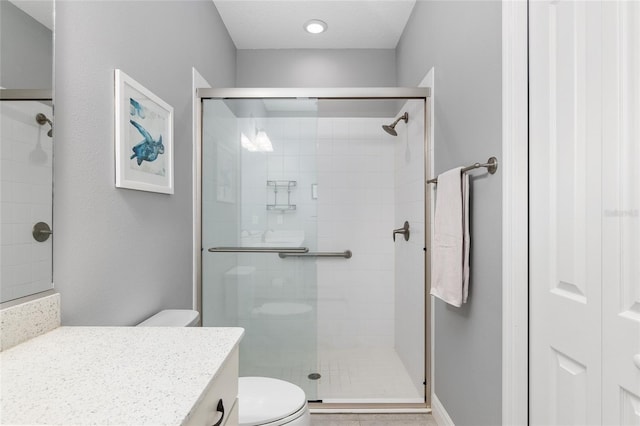 bathroom featuring toilet, vanity, and a shower with shower door